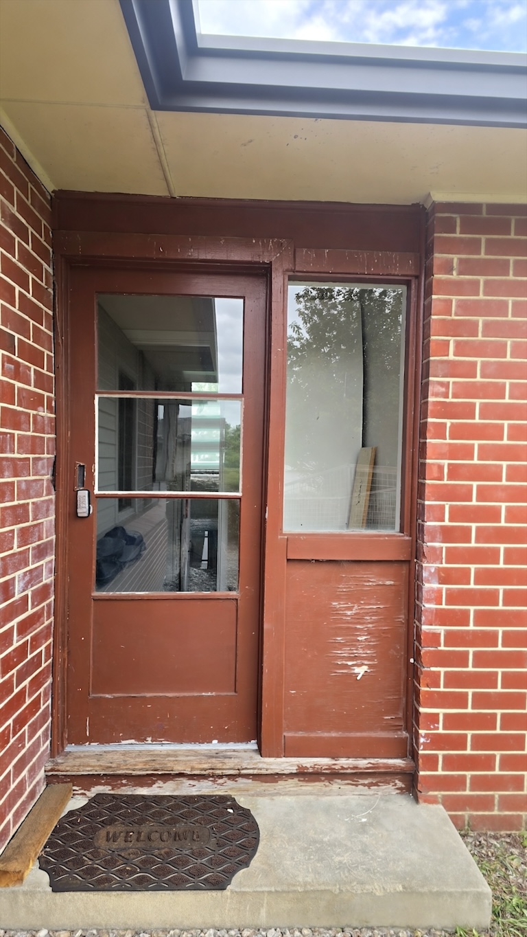 The original timber entrance door with flaking paint, before replacement
