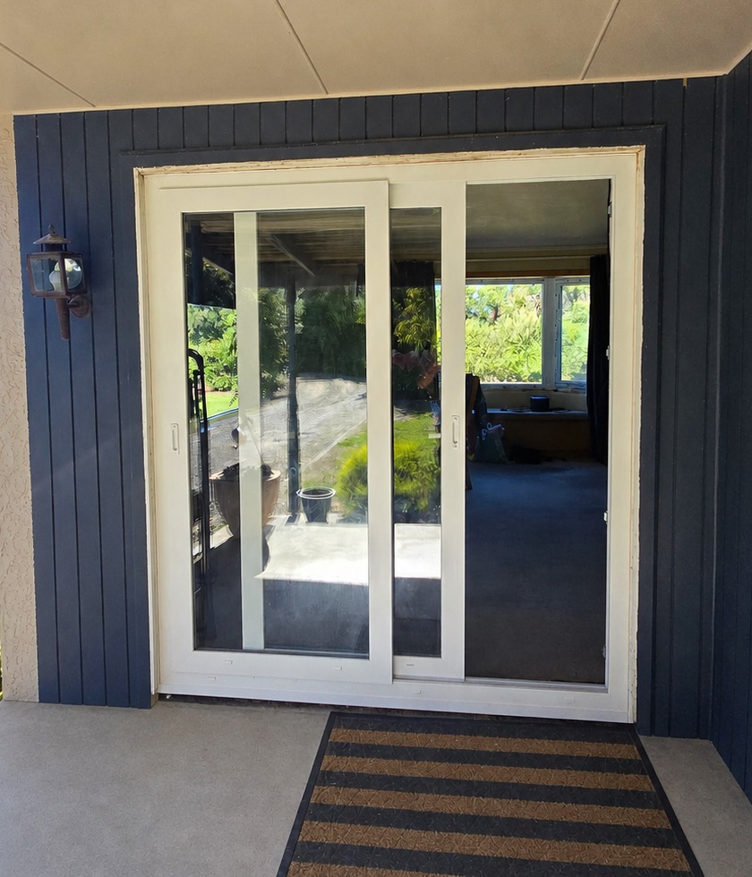uPVC sliding patio door standing open on a dark weatherboard home